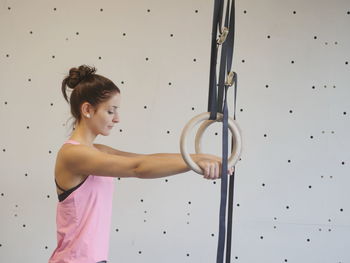 Side view of young woman exercising with gymnastic rings