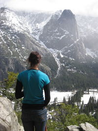 Rear view of woman standing on mountain during winter