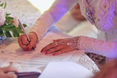 Midsection of woman holding paper with hand on table