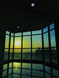 Silhouette building against sky during sunset seen through glass window