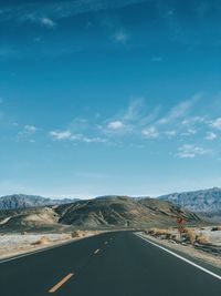 Road by mountains against blue sky