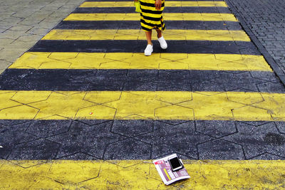 Low section of boy standing on yellow umbrella