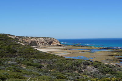 Scenic view of beach against clear blue sky