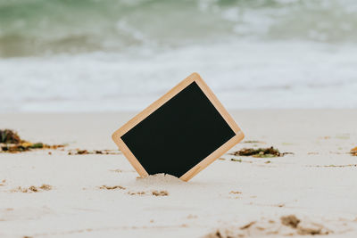 Close-up of mobile phone on sand at beach
