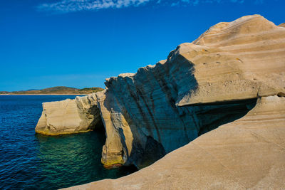 Rock formations in sea against blue sky