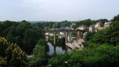 Viaduct over river amidst buildings against sky