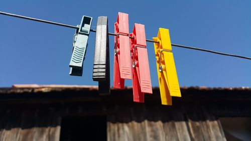 Low angle view of clothes pegs against blue sky