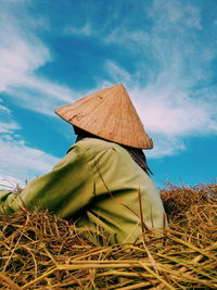 Side view of man sitting on field against sky