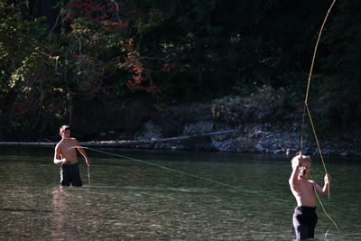 Shirtless people fishing in lake