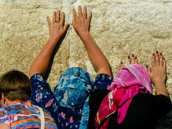 Rear view of women praying against wall