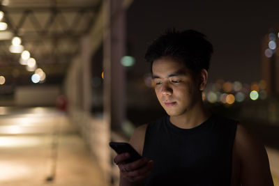 Portrait of young man using mobile phone at night