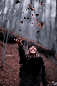 Portrait of young happy girl throws leaves in the air
