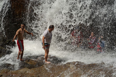 Full length of people splashing water in sea