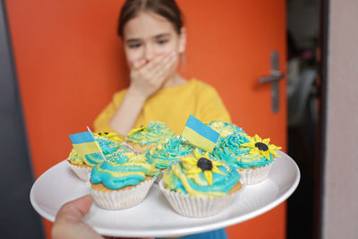 Ukrainian girl for whom neighbors brought cupcakes with cream in yellow and blue colors for brunch