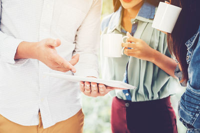 Midsection of woman holding paper while standing against wall