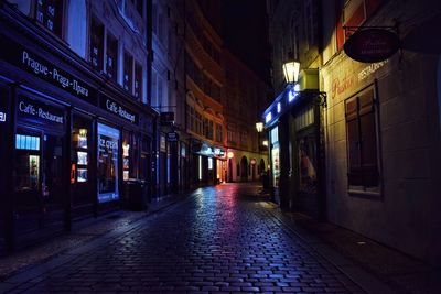 Illuminated street amidst buildings at night