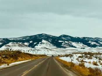 Road amidst snowcapped mountains against sky