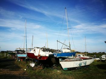 Boats moored at harbor against blue sky