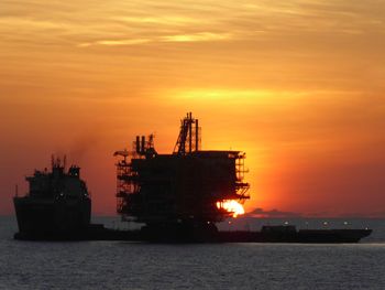 Ship in sea against orange sky