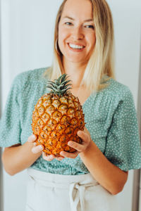 Close up of a woman holding an azorean pineapple and smiling