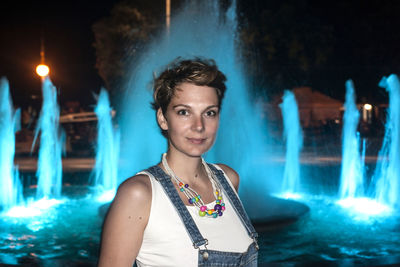 Portrait of woman against blue waterfall at night