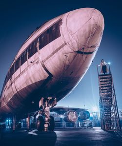 Man standing on airplane against sky at night