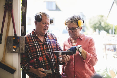 Senior couple discussing over digital tablet while standing at workshop doorway