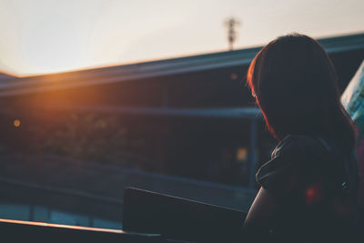 Rear view of woman against sky during sunset