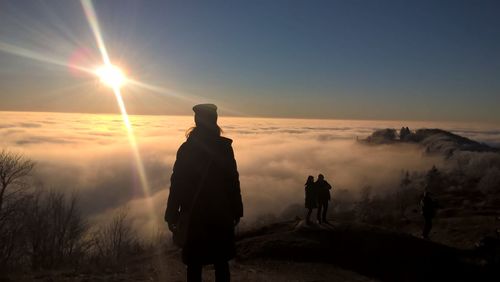 Silhouette people standing on landscape against sky during sunset