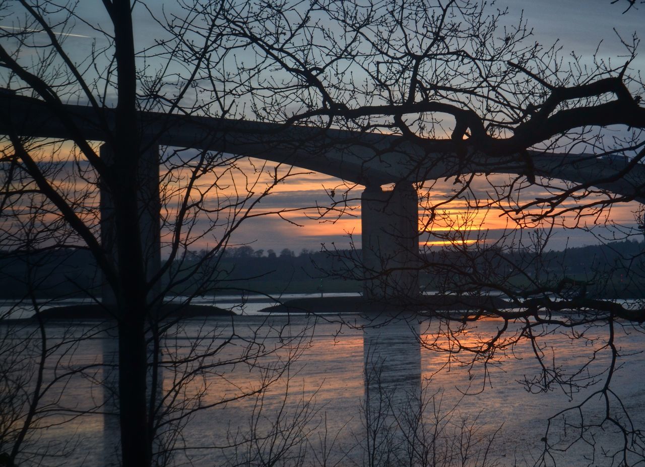 bare tree, silhouette, sunset, water, branch, tree, sky, built structure, architecture, building exterior, reflection, tranquility, river, nature, dusk, lake, scenics, tranquil scene, cloud - sky, beauty in nature