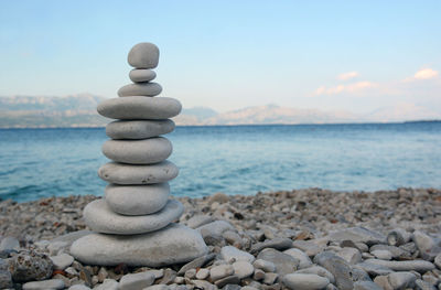 Stack of pebbles by sea against sky