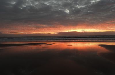 Scenic view of sea against dramatic sky during sunset