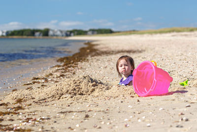 Portrait of girl playing with sand at beach