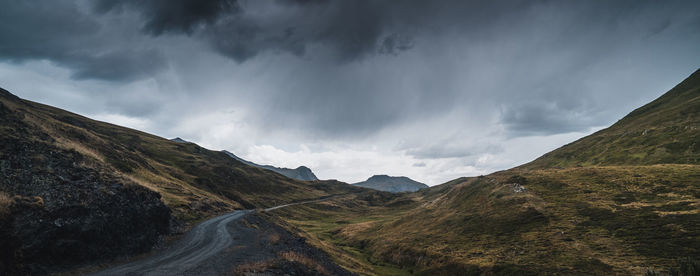 Scenic view of road by mountains against sky