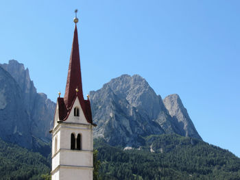 Low angle view of building and mountains against clear blue sky