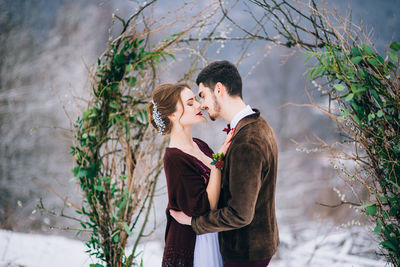 Young couple standing against plants