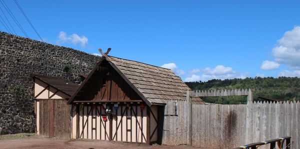 Wooden cottage by building against sky