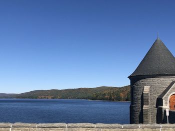 Lake by building against clear blue sky