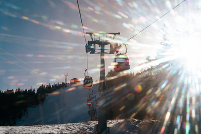 Low angle view of cable car over winter mountaina against sky