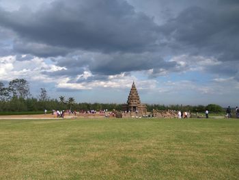 Group of people in front of building against cloudy sky