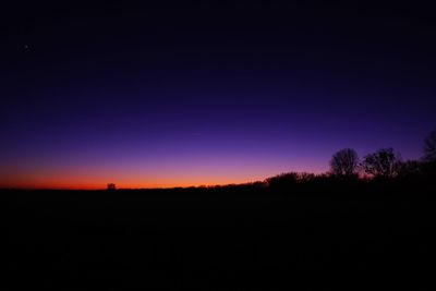 Silhouette trees against clear sky at night