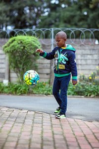 Full length of boy playing with ball on street