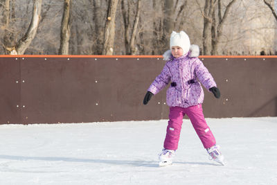 Cute girl ice skating on land during winter