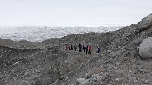 People on rock against sky