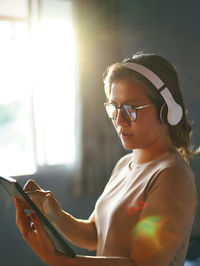 Mid adult woman using digital tablet wearing headphones