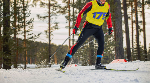 Low section of man skiing on snow covered field