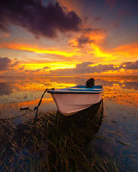 Boat moored on beach against sky during sunset