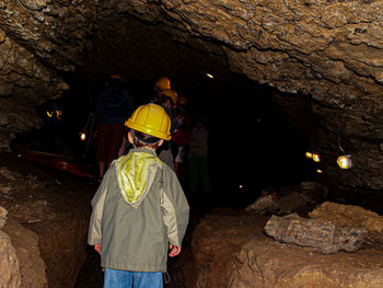 Rear view of men standing on rock in cave