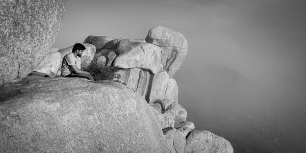 People sitting on rock against sky