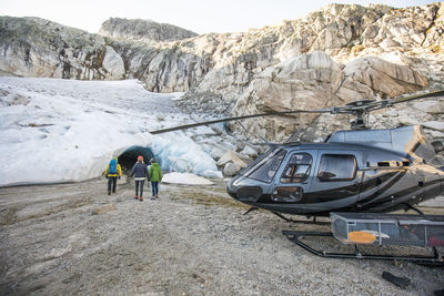 A mountain guide approaches a glacial ice cave with tour clients.